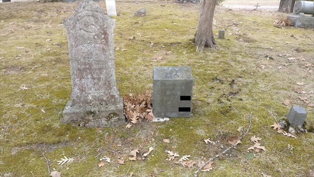 The headstone, with years masked.