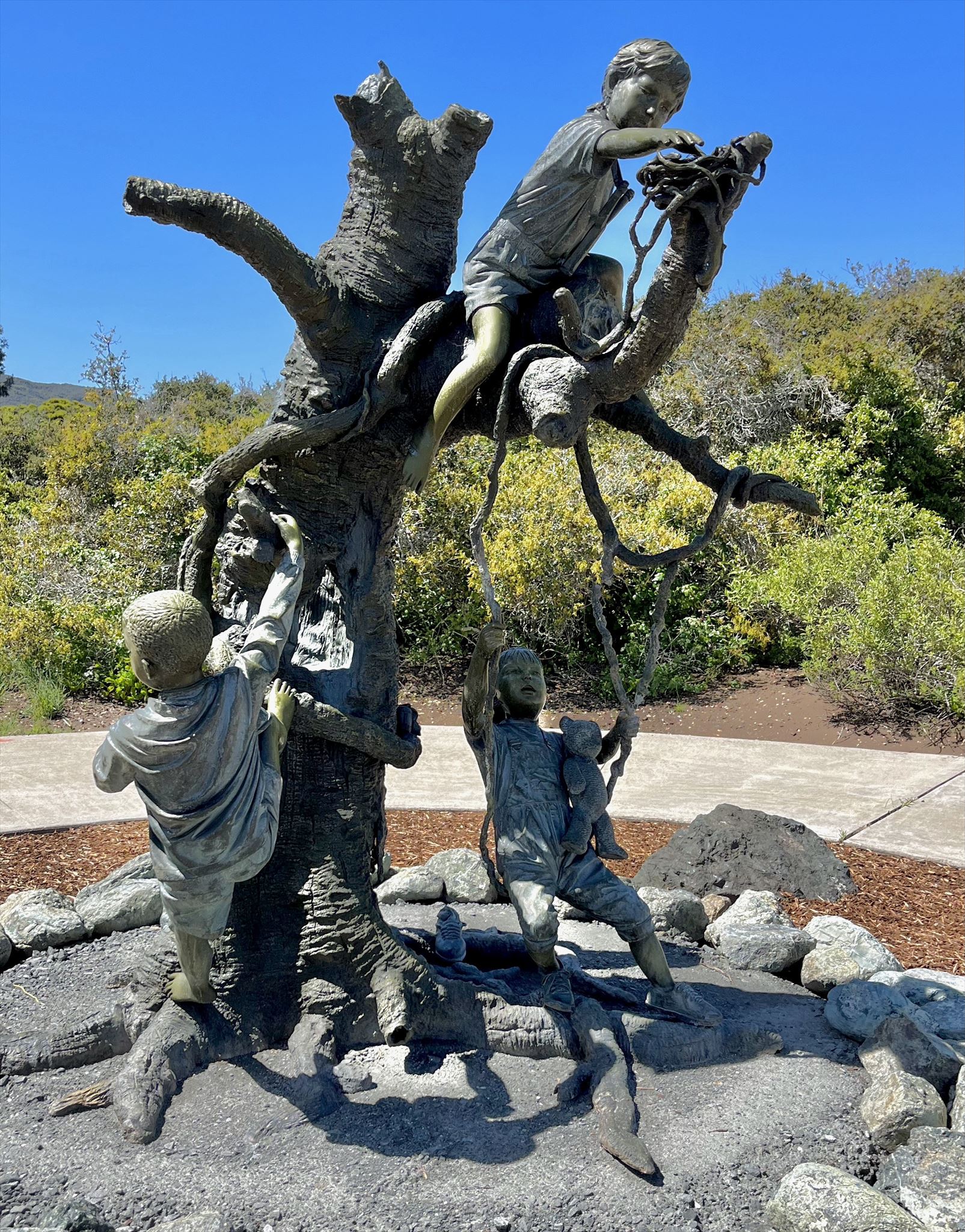 Jim Davidson bronze sculpture of four children playing on a tree