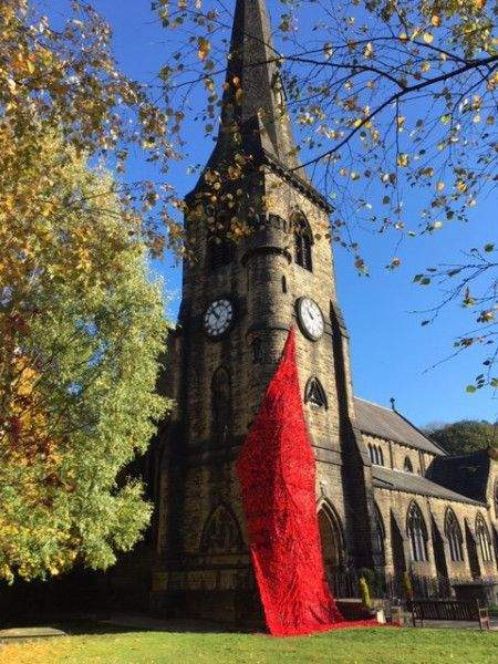 Picture shows a Church with a Steeple and a draping poppy decoration.