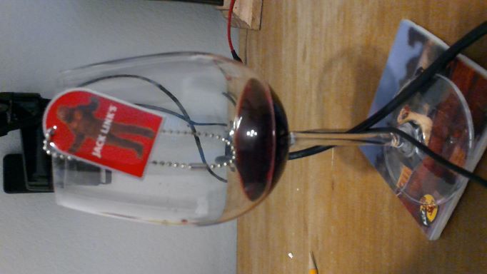 Jack Links trackable hanging from an almost empty glass of wine.